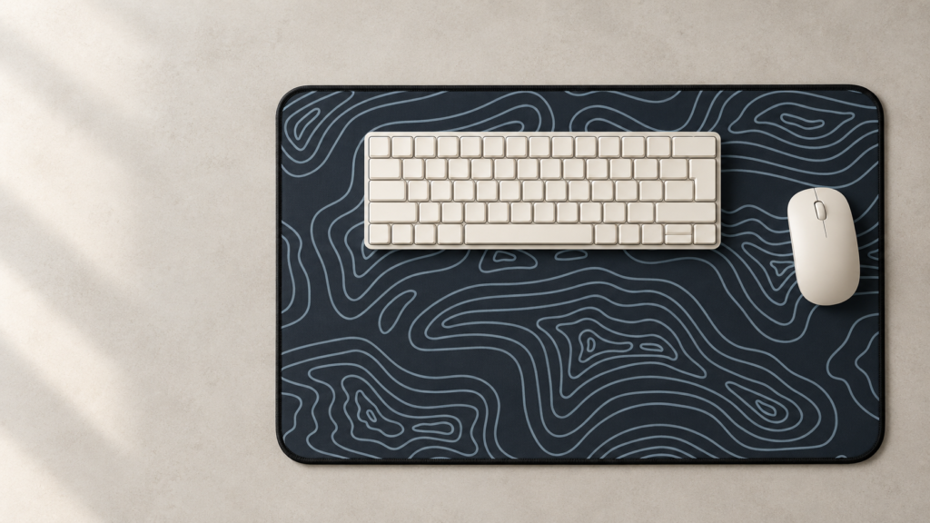Topographic desk mat viewed from above with a cream keyboard and mouse.
